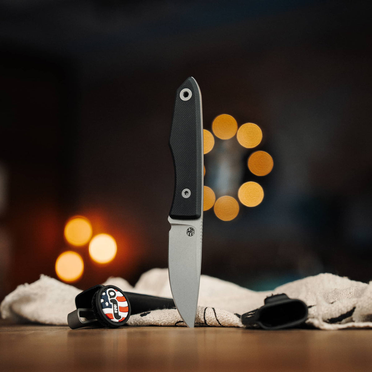 Lookout knife with Black G10 handle displayed beside two Kydex sheaths
