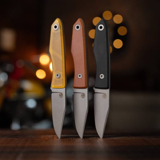 Three USA Lookout knives with Ultem, Natural Micarta, and Black G10 handles displayed upright
