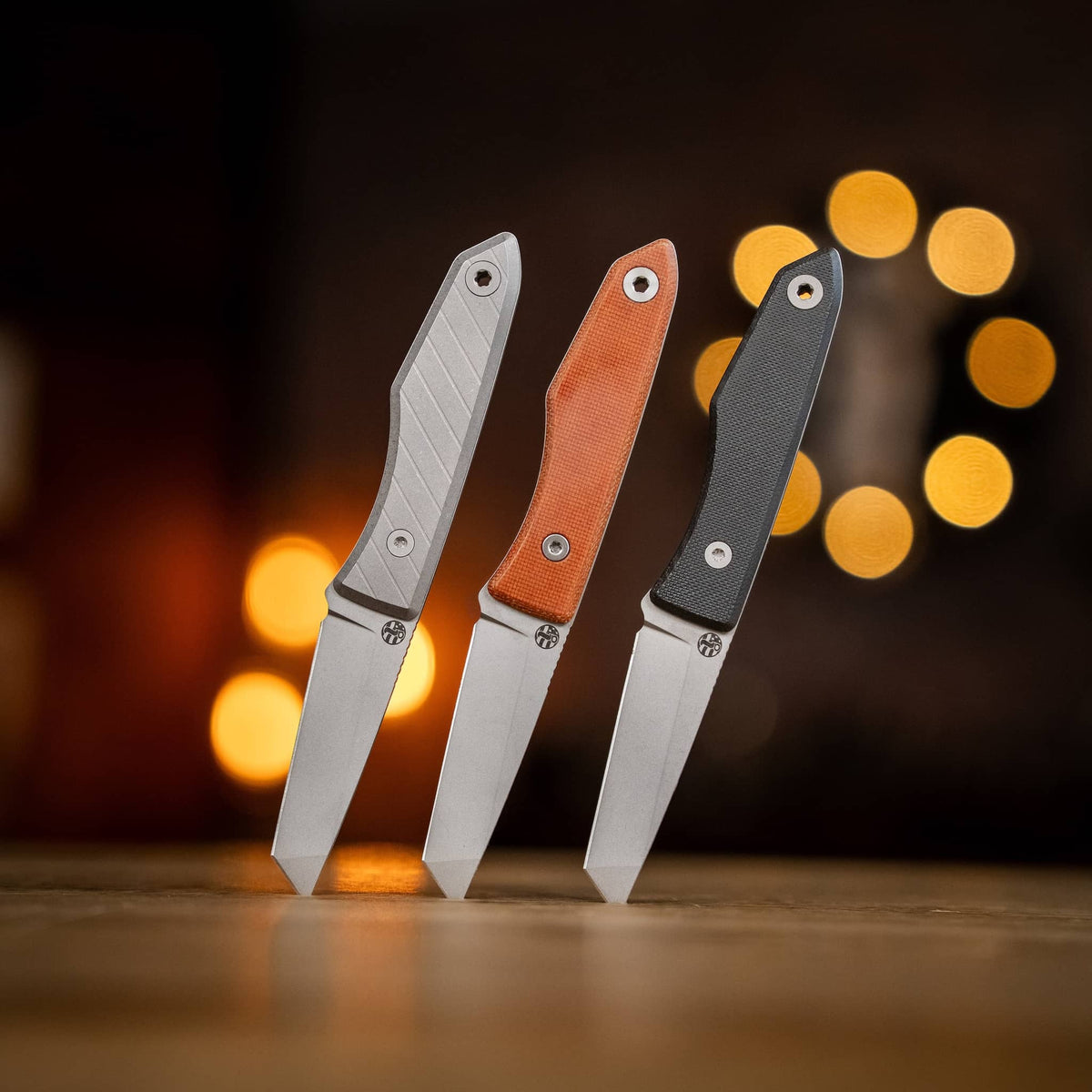 Three Lookout tanto knives with titanium, Natural Micarta, and Black G10 handles
