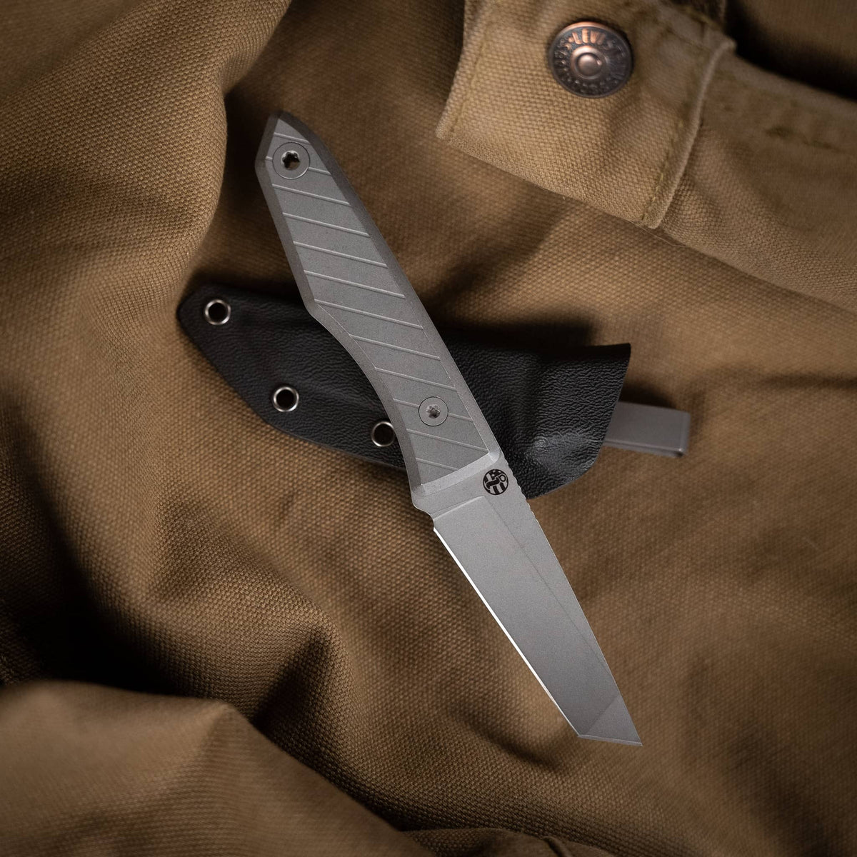 Lookout tanto knife with titanium handle and Kydex sheath on brown canvas
