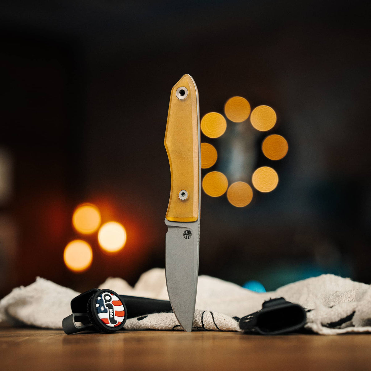 Lookout knife with yellow Ultem handle displayed beside two Kydex sheaths
