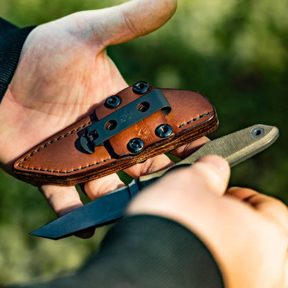 Knife and sheath outdoors: Hands holding the Lookout reverse tanto knife and brown leather sheath outdoors
