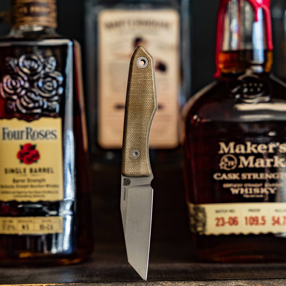 Bottles: Big Idea Design Lookout knife with green Micarta handle displayed in front of whiskey bottles