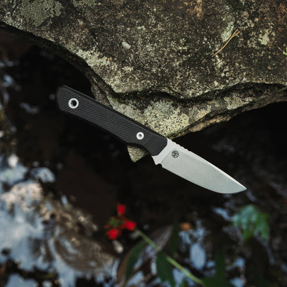 Cloudland MagnaCut knife with Black G10 handle resting on a rock above flowing water