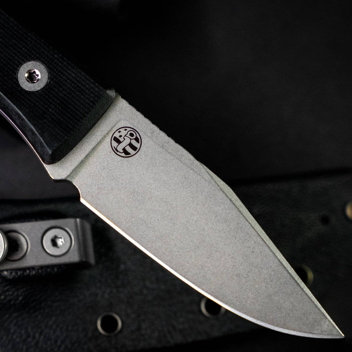Close-up of the Lookout blade finish and Big Idea Design logo beside a Kydex sheath
