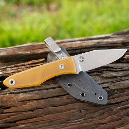 Lookout knife with translucent yellow Ultem handle and Kydex sheath on weathered wood
